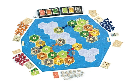 Pełna plansza do gry Catan z sześciokątnymi kafelkami, kartami i żetonami surowców rozłożonymi na stole do gry.